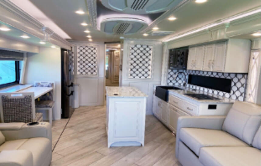 Inside picture of an American Dream by American Coach RV. Shows teh kitchen and seating areas.