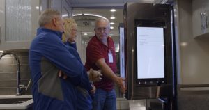 Image of a man showing 2 people the features inside an American Coach RV