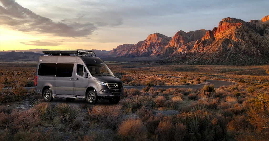 Picture of silver Class B motorhome in the desert during a sunset