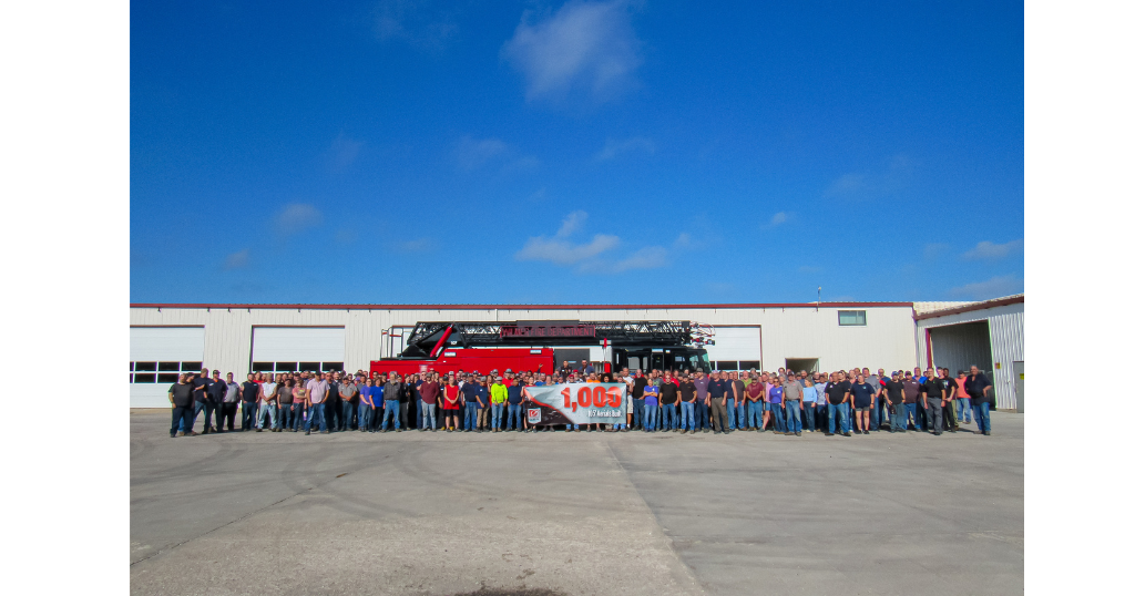 Large group of people outside with fire truck behind them.