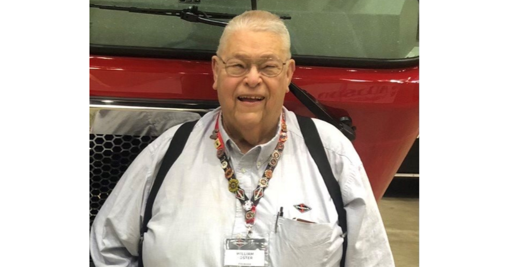 Older man smiling with fire truck behind him