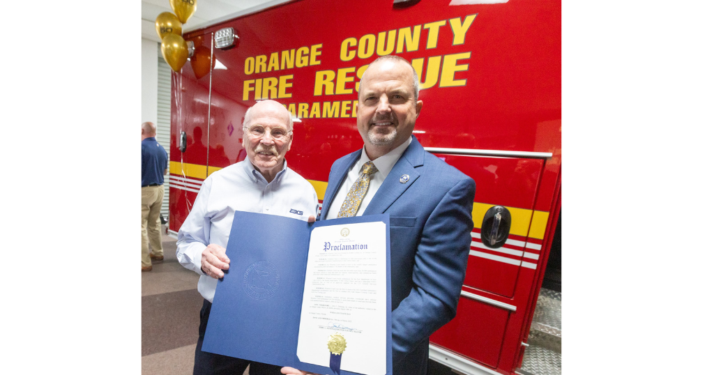 Two men standing by an ambulance, holding a piece of paper